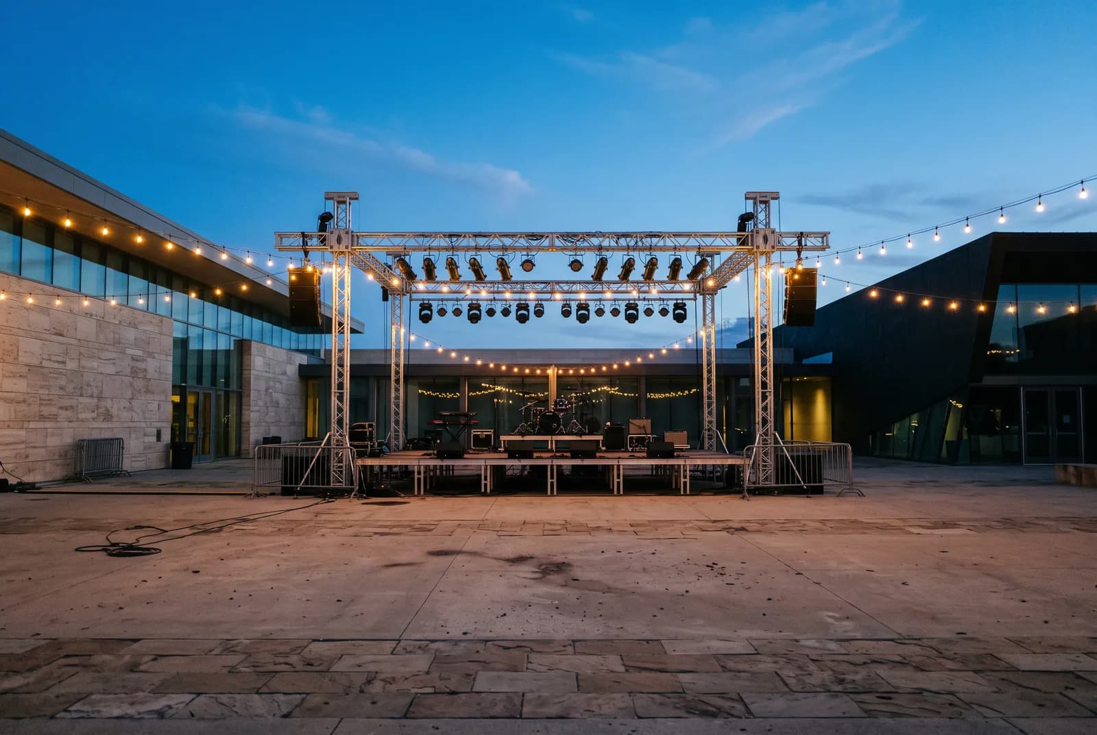 Escenario vacío con torres de focos y guirnaldas de luces a la hora azul