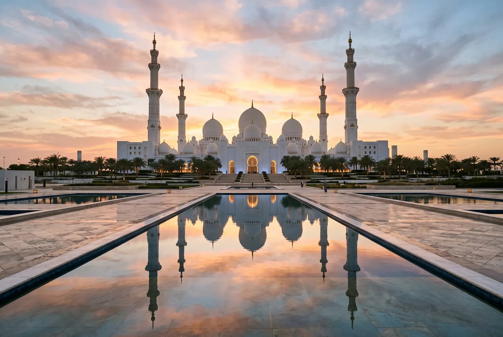 Cúpulas y cuatro minaretes reflejados en un estanque bajo un cielo rosado